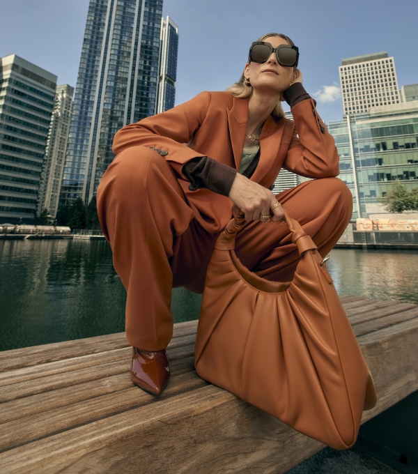 A model wearing head-to-toe rust-coloured outfit with a luxury designer bag.