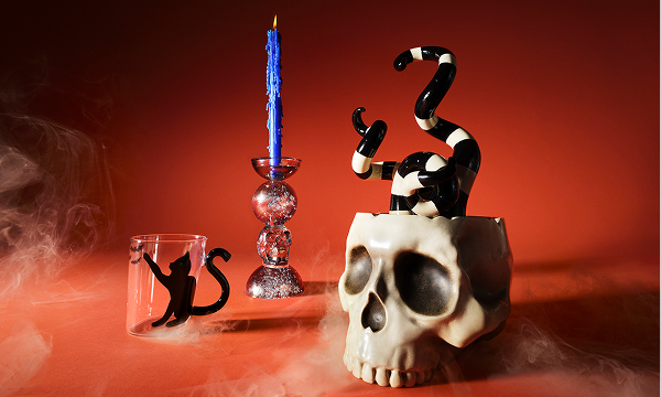 A skull ornament and candlestick against a spooky orange background