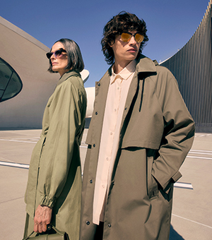 A male and female model wearing statement sunnies and green overcoats. 
