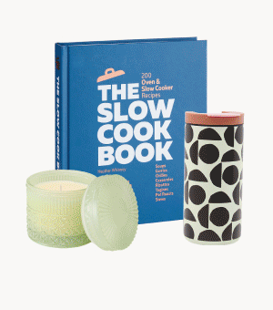 A blue cookbook next to a green glass candle and patterned water bottle. 