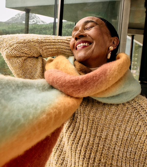 Woman wearing a knitted jumper and thick scarf.