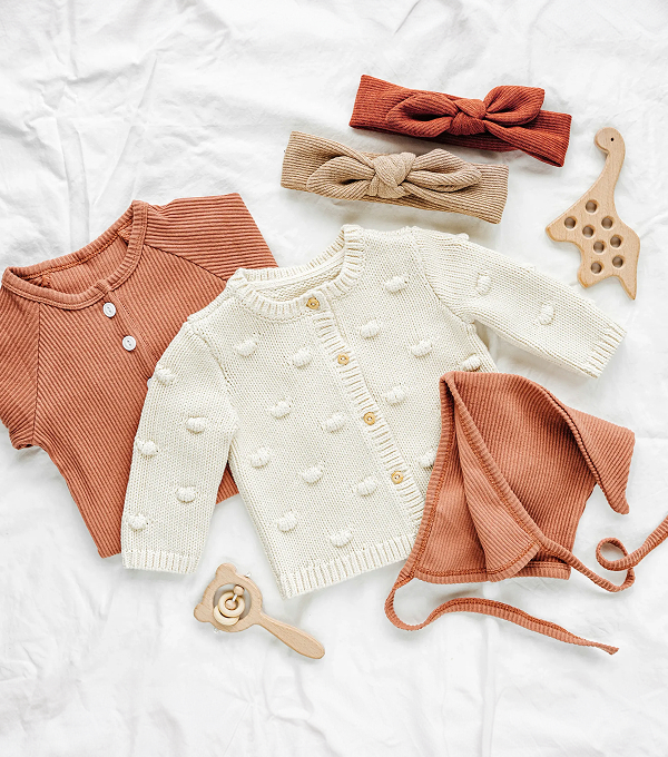 Baby clothing and accessories in neutral tones.